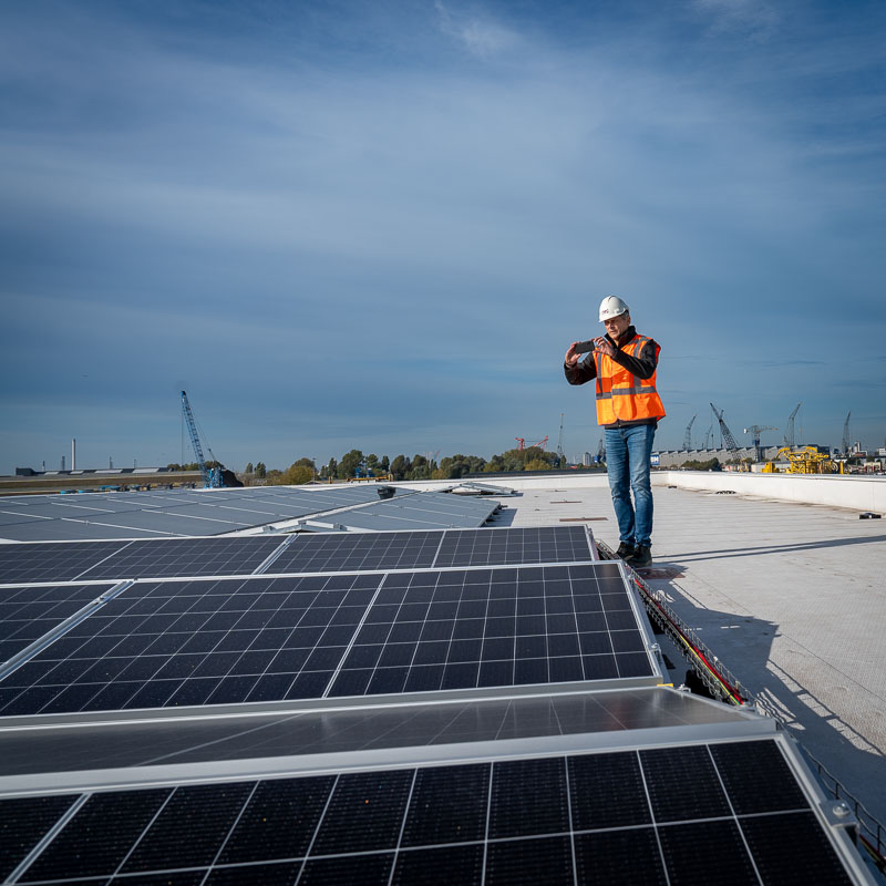 RPS inspecteur inspecteert dak van gebouw met zonnepanelen